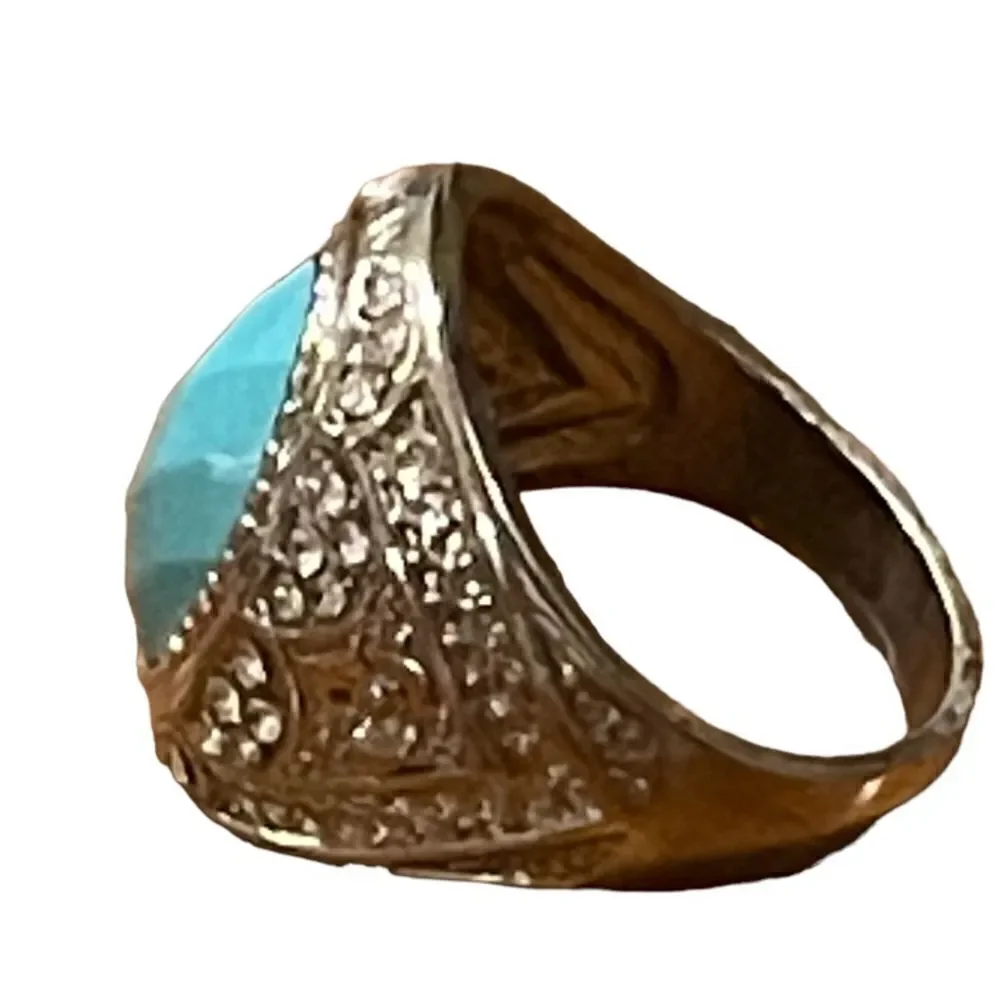 Costume jewelry silver tone ring with turquoise color acrylic center stone.